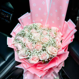 Pink rose bouquet wrapped in pink paper with white filler flowers