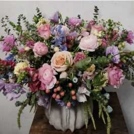 Large pastel bouquet in a white vase with pink, lavender, and peach flowers