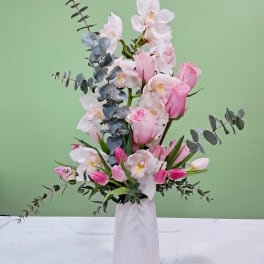 Pink and white orchid arrangement in a white vase