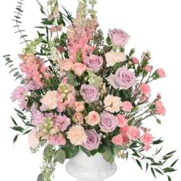 Large pastel floral arrangement in a white pedestal vase
