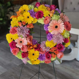 Colorful floral wreath on a metal stand with roses and daisies