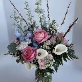 Pink roses and white calla lilies in a glass vase with blue and white flowers