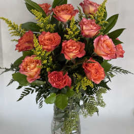 Coral and pink roses arranged in a clear glass vase
