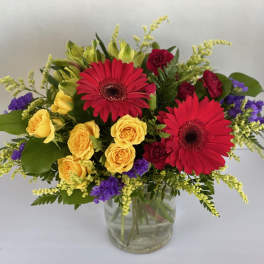 Bouquet of red gerbera daisies and yellow roses in a glass vase