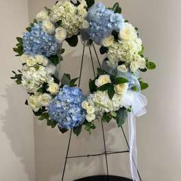 Blue and white floral wreath on a stand with a white ribbon