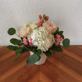 Pink roses and white hydrangeas arranged in a white vase