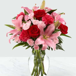 Pink lilies and red roses arranged in a clear glass vase