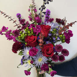 Bouquet of red roses, purple blooms, and lavender daisies