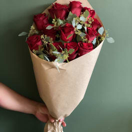 Hand-tied bouquet of red roses wrapped in brown paper