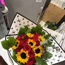 Bouquet of red roses and yellow sunflowers wrapped in patterned paper