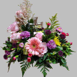 Pink and purple floral arrangement with a silver cross centerpiece