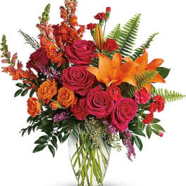 Bright bouquet of roses and orange lilies in a clear glass vase