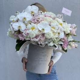 Large pastel bouquet with white orchids and pale roses in a gray hatbox