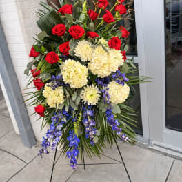Standing floral spray with red roses, cream blooms, and blue orchids