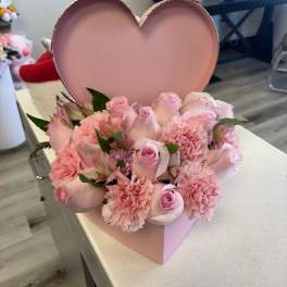 Pink roses and carnations arranged in a heart-shaped box