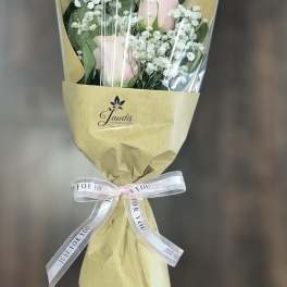 Bouquet of pale pink roses with white baby's breath in tan wrapping
