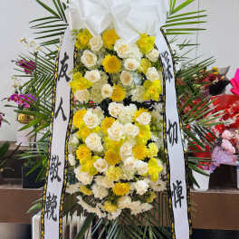 Tall funeral standing spray with white and yellow flowers and ribbon streamers