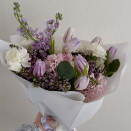 Handheld bouquet of pink and white flowers wrapped in white paper