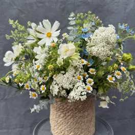 Mixed white and blue flowers arranged in a rope-wrapped vase