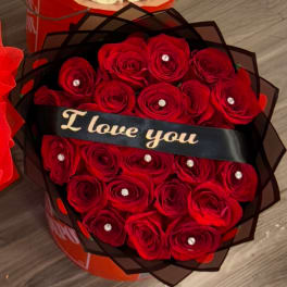 Red roses wrapped in black paper with a "I love you" ribbon