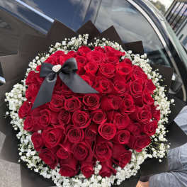 Large bouquet of red roses with white baby's breath and a black ribbon