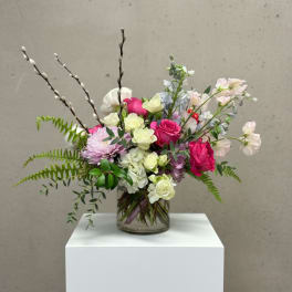 Mixed pink and white flowers arranged in a clear glass vase