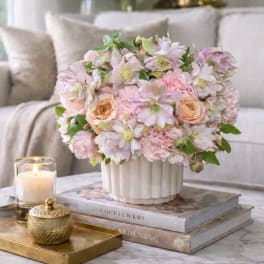 Blush and cream floral arrangement in a white vase on a table