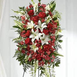 Standing floral spray with red roses and white lilies on a black easel