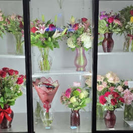 Assorted flower bouquets arranged in vases on display shelves