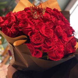 Bouquet of red roses wrapped in brown paper with a decorative crown