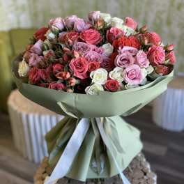 Large bouquet of pink, red, and white roses wrapped in pale green paper