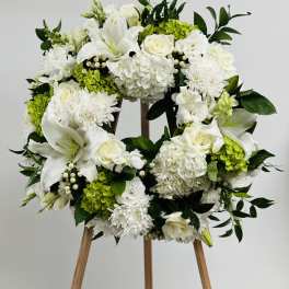 White floral wreath on a wooden easel with green accents