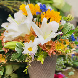 Bouquet of white lilies, yellow and peach daisies in a gray vase