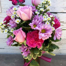 Pink roses and purple daisies in a vase with a butterfly pick
