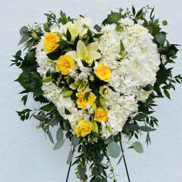 Heart-shaped white and yellow floral spray on a stand