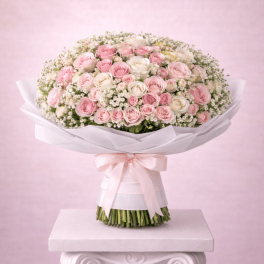 Large bouquet of pink and white roses wrapped in white paper with a ribbon