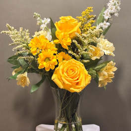Yellow roses and daisies arranged in a clear glass vase