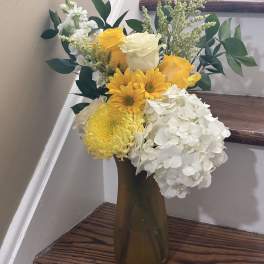 Yellow and white roses with white hydrangeas in a tall vase