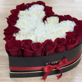 Heart-shaped box of red roses and white carnations with a red ribbon