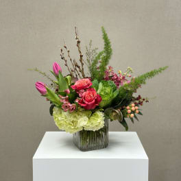 Pink roses and tulips in a glass vase with green hydrangea
