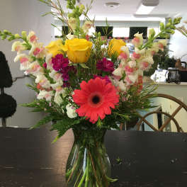 Mixed bouquet in a glass vase with yellow roses and pink gerbera daisies