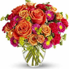 Orange roses and pink daisies in a clear glass vase