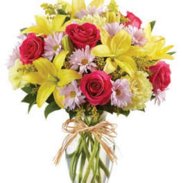 Bouquet of yellow lilies, pink roses, and daisies in a glass vase