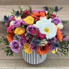 Colorful bouquet of roses, gerbera daisies, and a white anemone in a striped vase