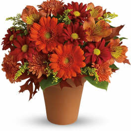Orange and red mixed bouquet in a brown cone vase