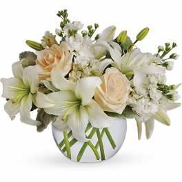 White lilies and pale roses in a round glass vase
