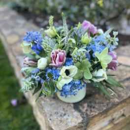 Blue and pink mixed flower arrangement in a white vase