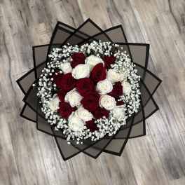 Round bouquet of red and white roses with baby's breath in black wrap