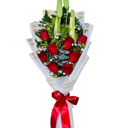Bouquet of red roses and white lilies wrapped in white paper with a red ribbon