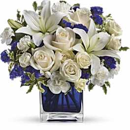 White lilies and roses arranged in a blue glass vase